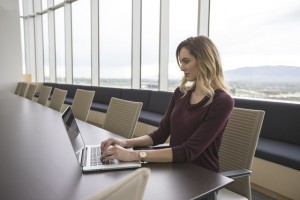 Professional woman working on laptop in a modern office conference room.