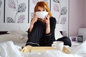 Woman relaxing in bed with breakfast tray, enjoying a cozy morning.
