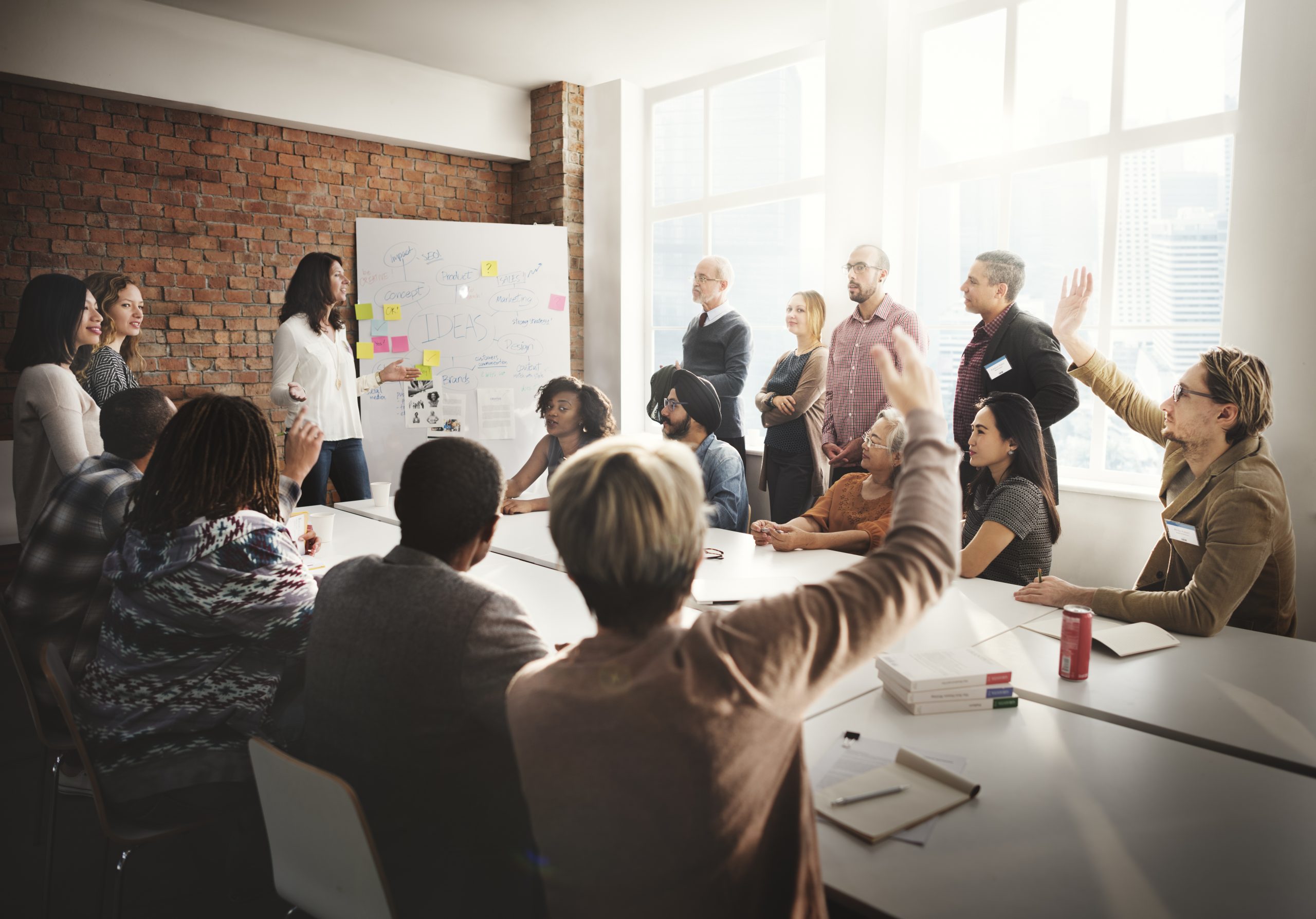 Diverse group of professionals engaged in a workshop with raised hands.