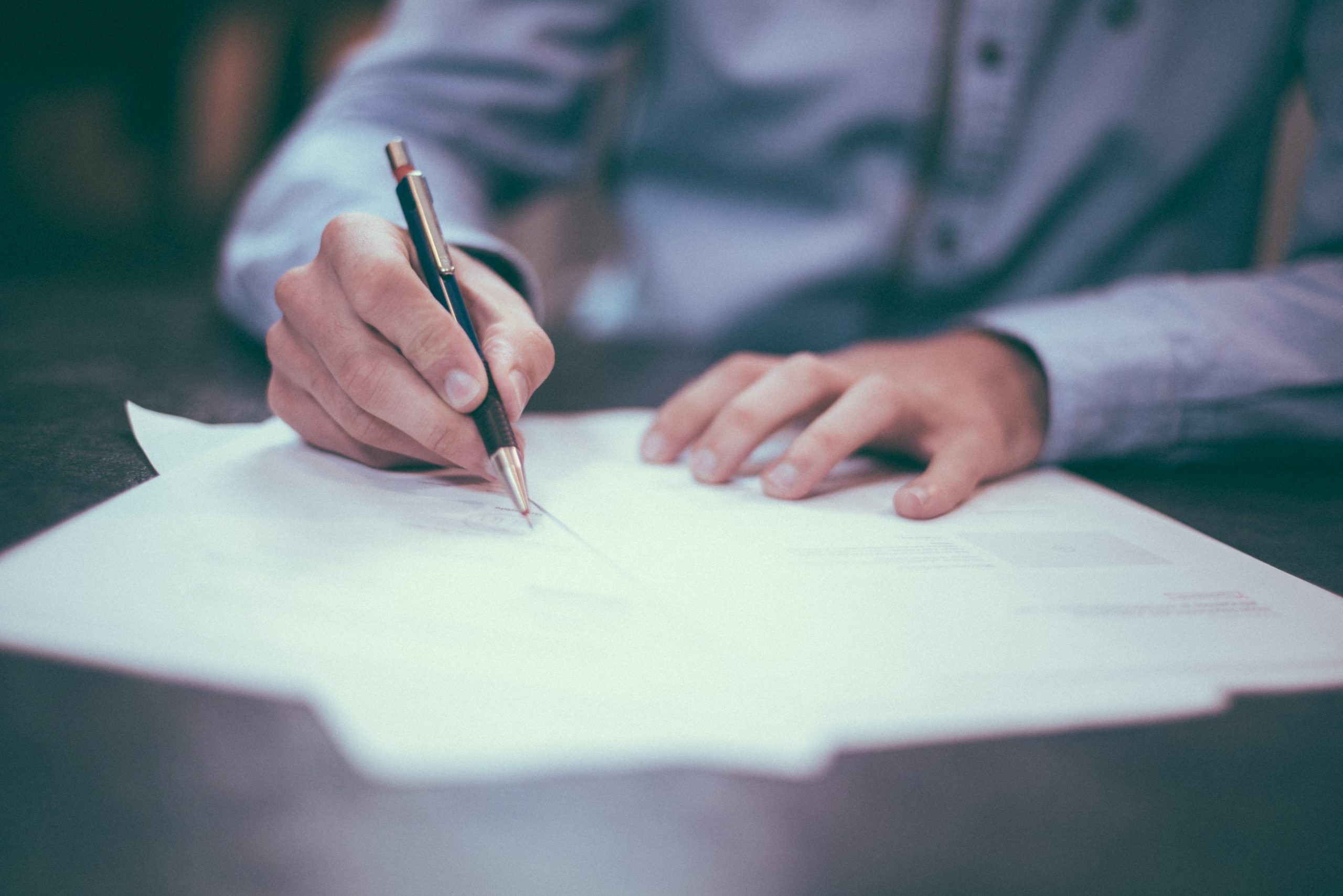 Close-up of a person's hand writing on official documents.