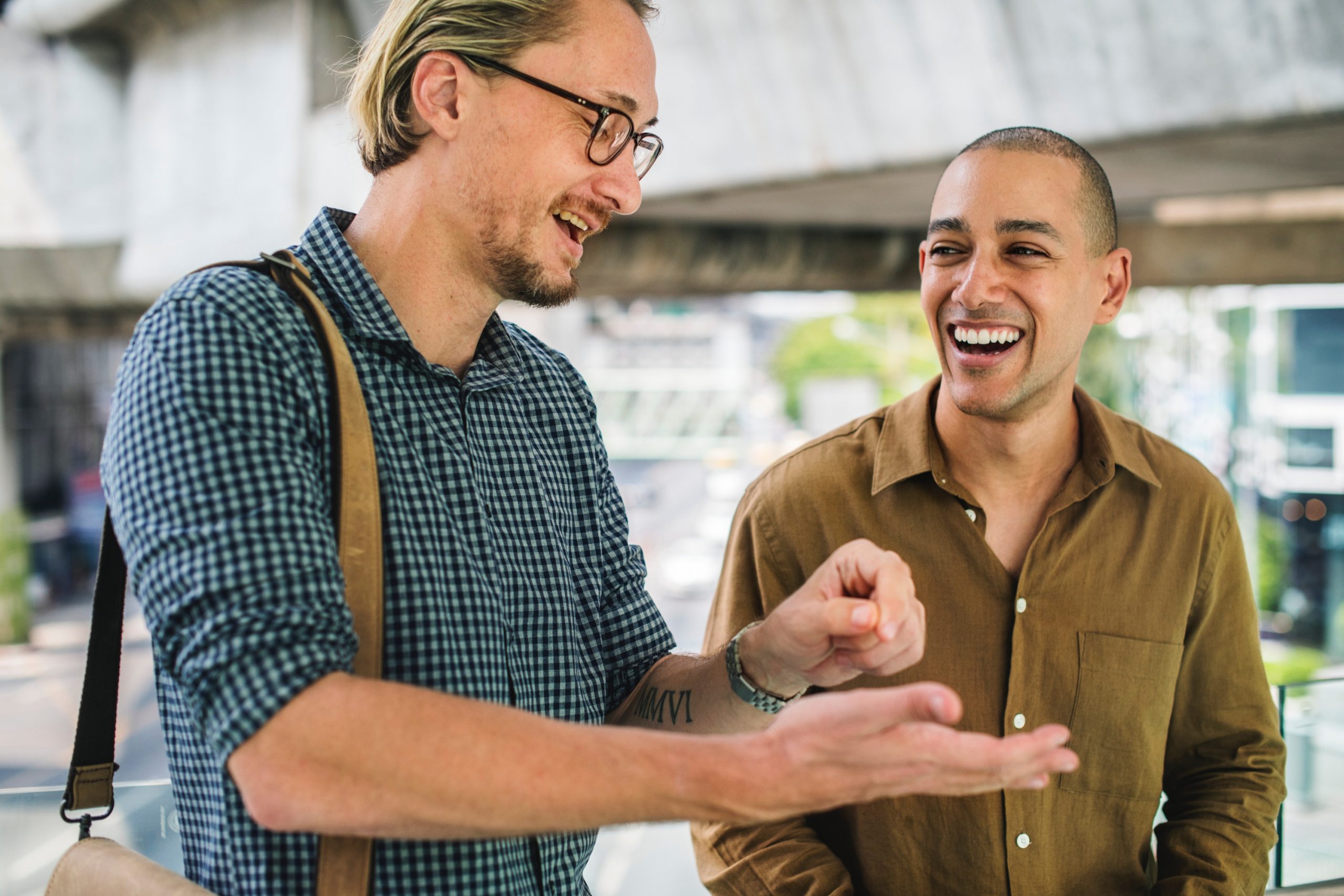 Two professionals laughing and sharing a fist bump in an urban setting.