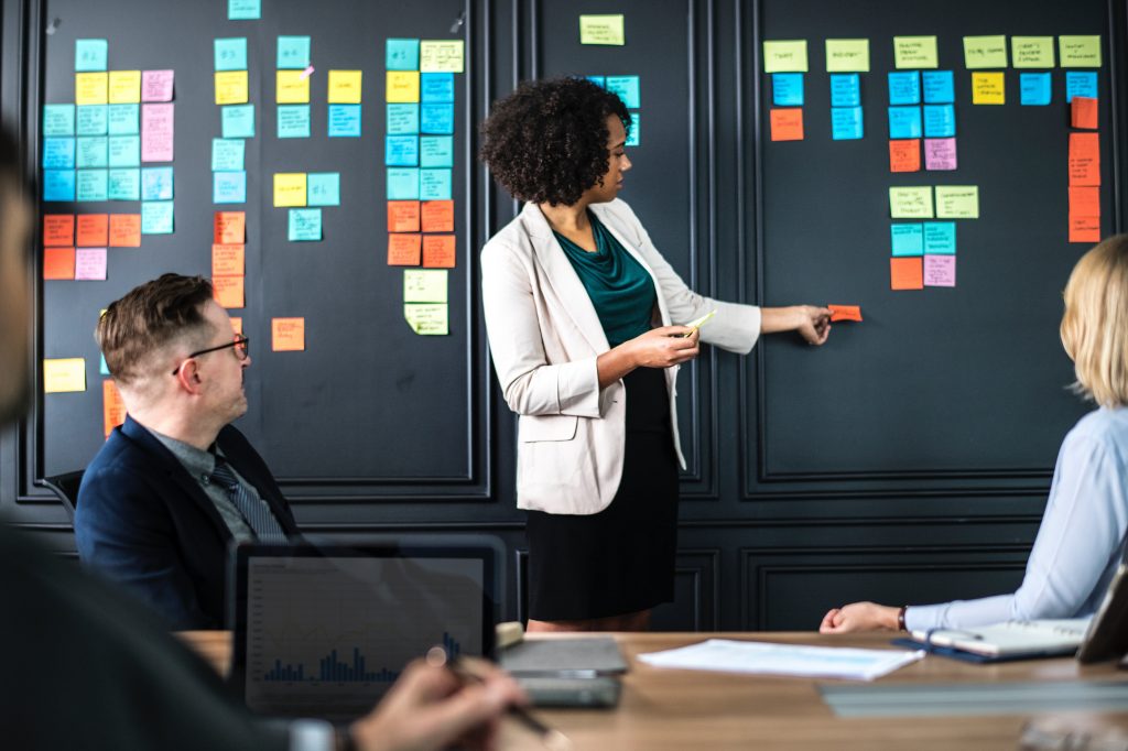 Professional presenting strategic ideas on a colorful sticky note wall to colleagues.