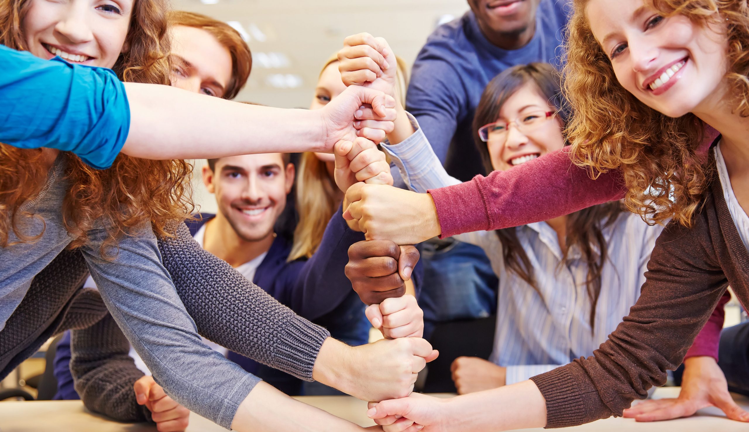 Diverse team stacking hands in a gesture of unity and teamwork.