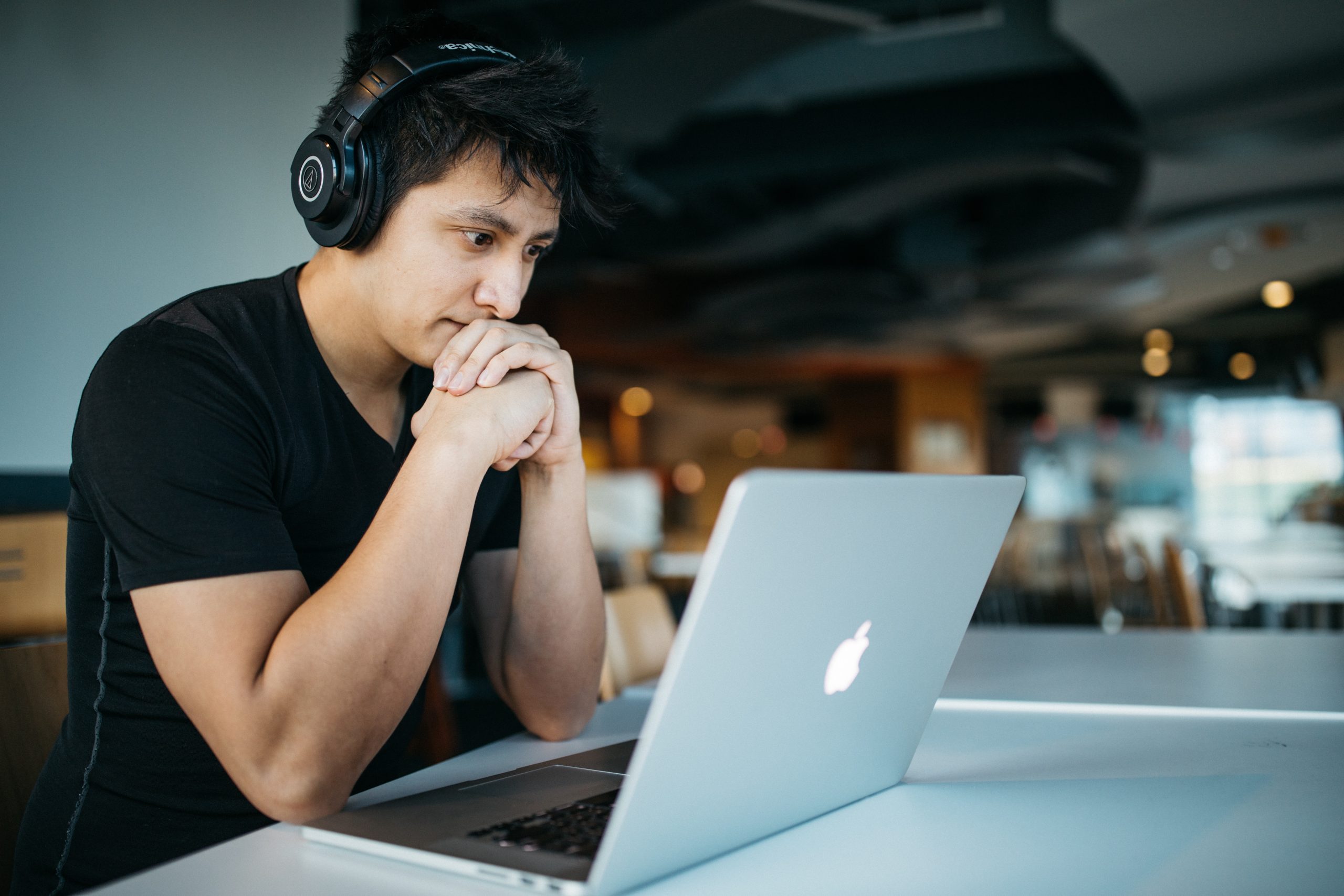Focused man with headphones using laptop in a modern workspace.