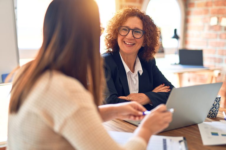 Smiling businesswoman in meeting with colleague in sunny office.