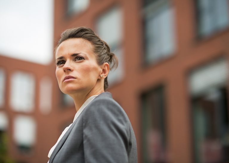 Determined professional woman in business attire outside office buildings.