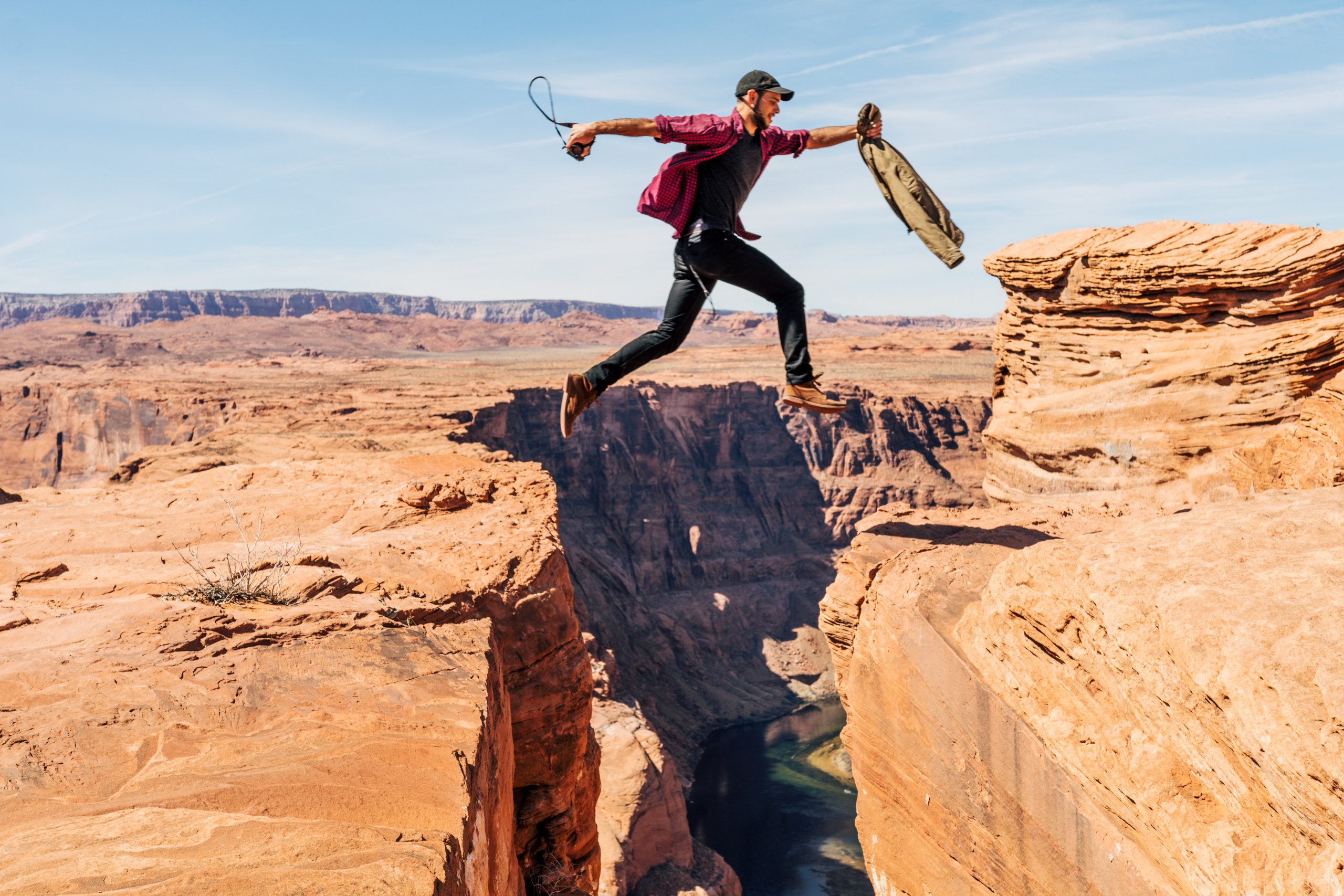 Adventurous person leaping across a canyon gap, symbolizing challenge and risk.