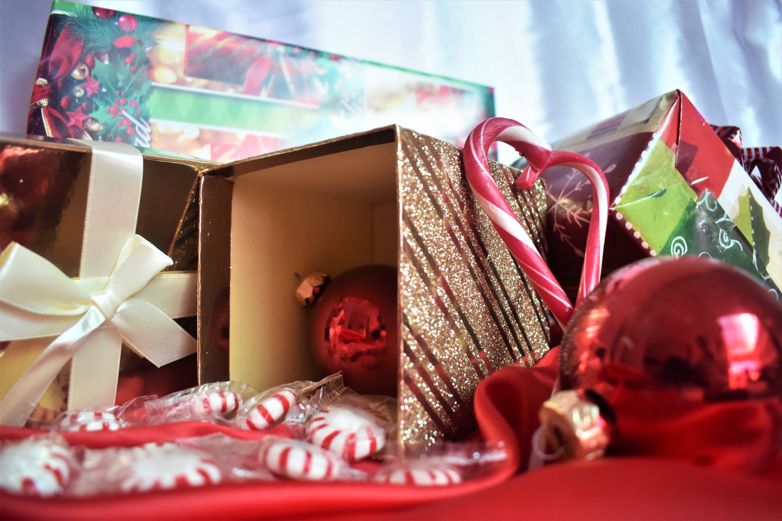Open box with festive Christmas decorations and candies, holiday spirit.
