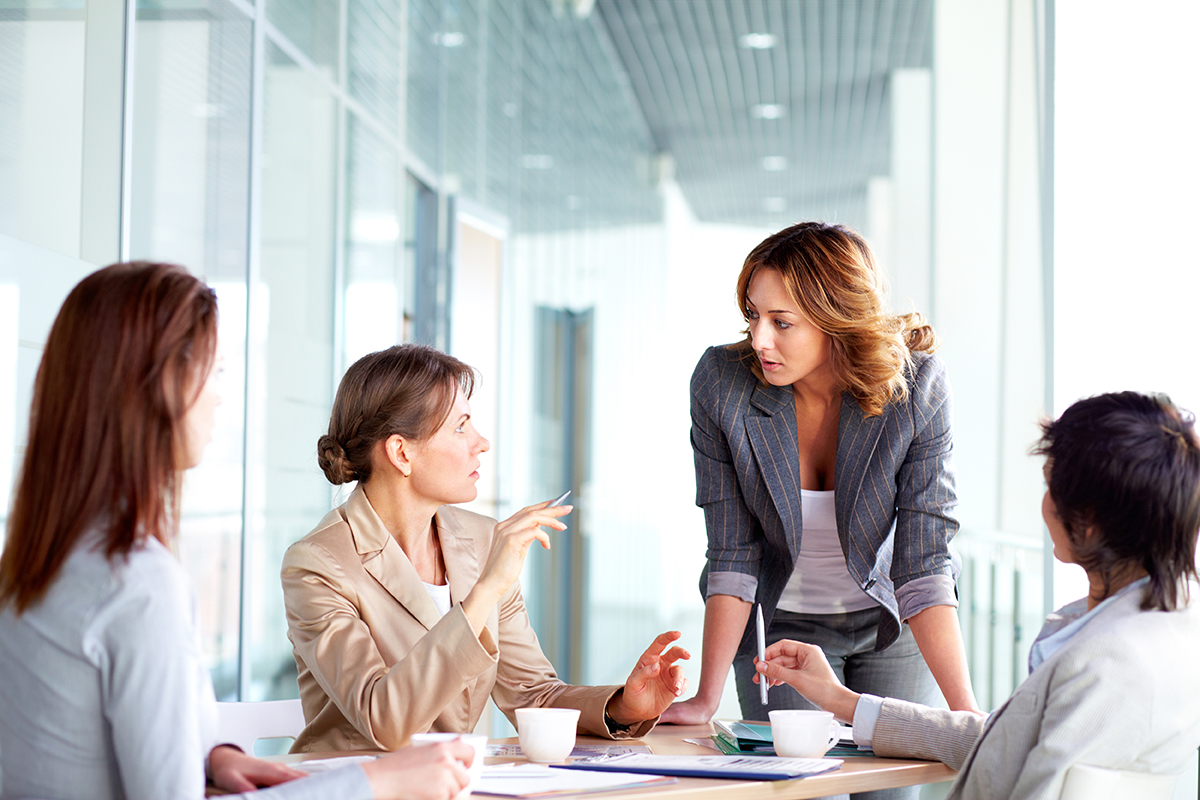 Four professionals engaged in a discussion around a table in a bright office setting.