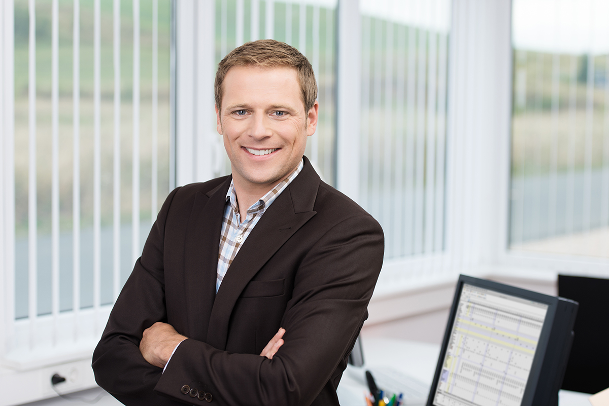 Confident businessman smiling in office environment.