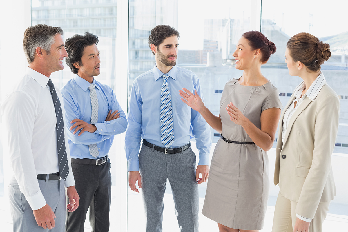 Business team engaged in a friendly conversation in a modern office with city views."