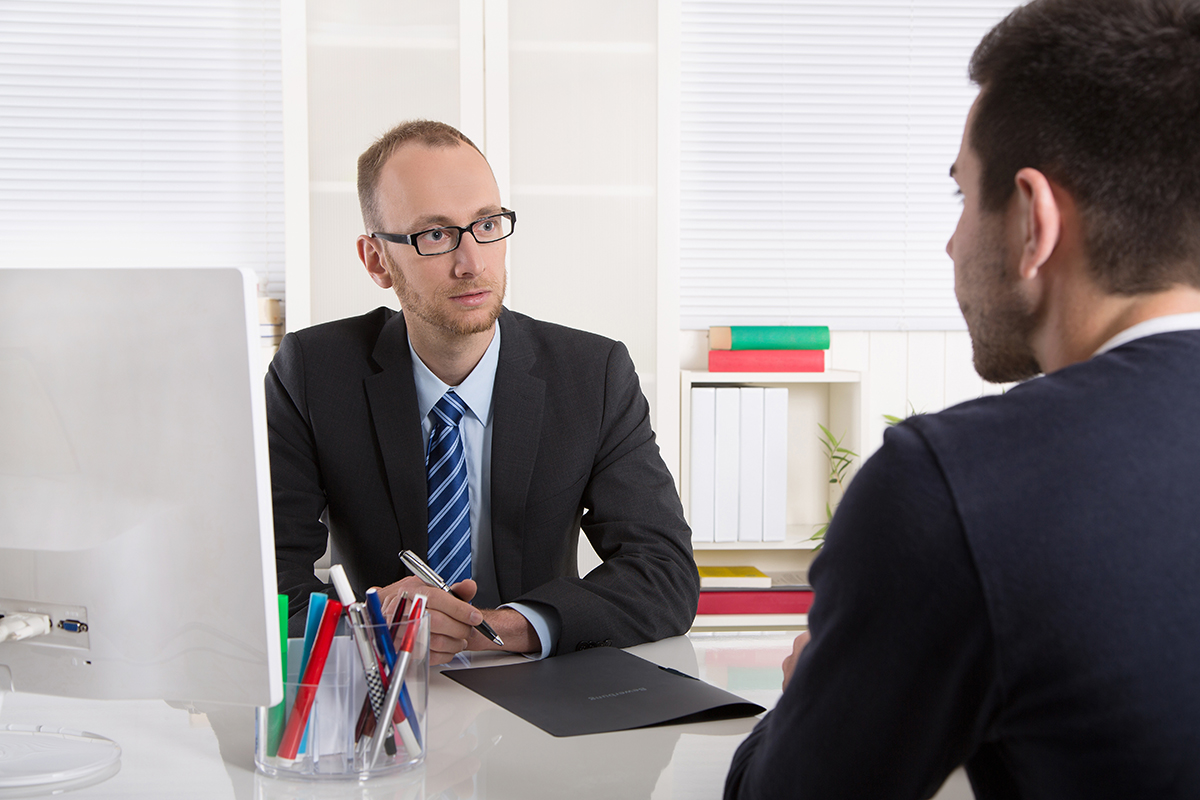 Two businessmen in a serious meeting, with one taking notes.