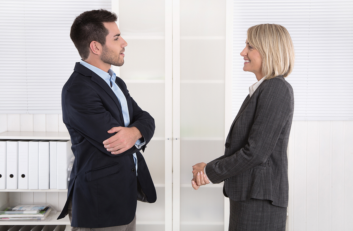 Two professionals in a business meeting, shaking hands in agreement in an office.