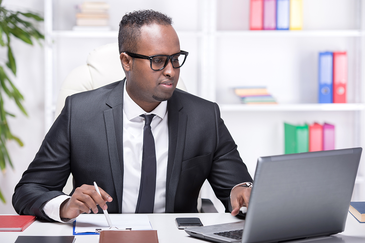 Focused businessman working on laptop in office.