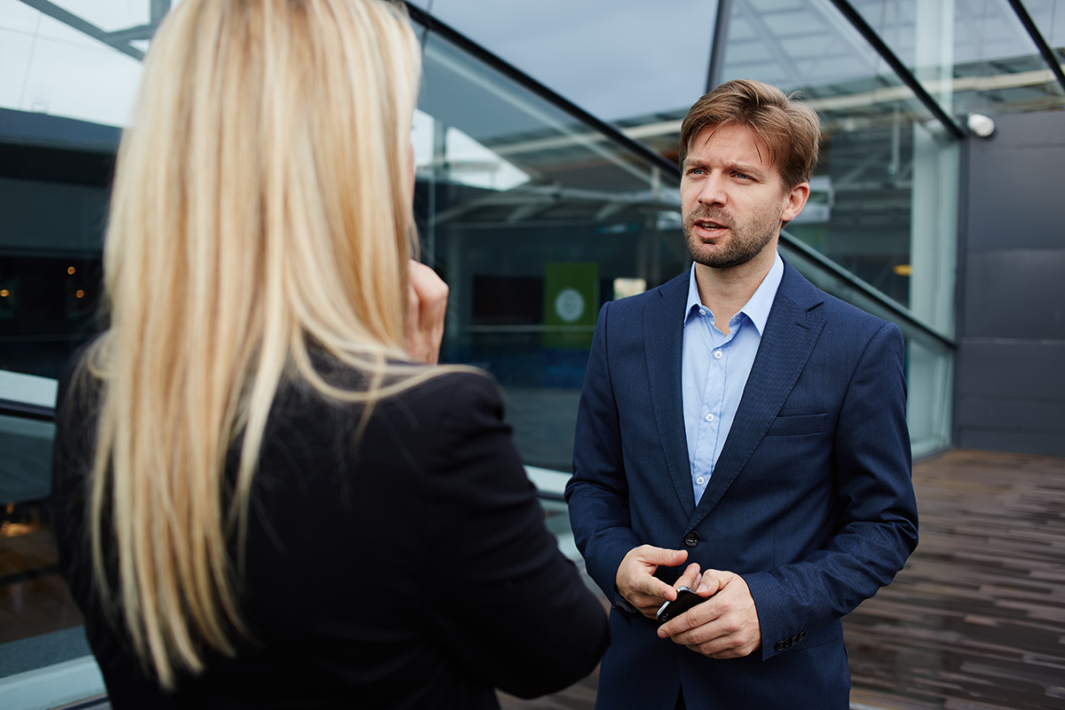 Two professionals in a serious discussion outside modern office buildings.