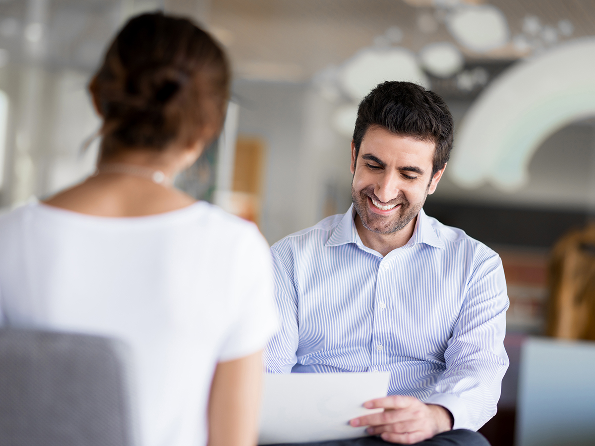 Smiling male manager reviewing documents with female colleague in office.