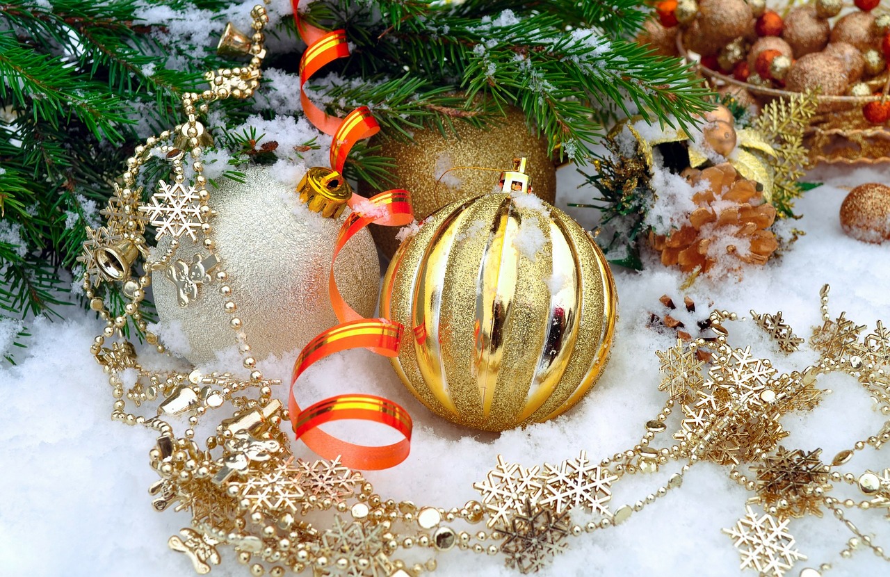 Golden Christmas ornaments and pine branches on snowy background.