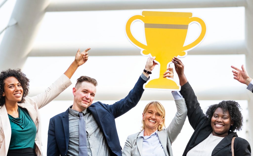 Diverse team celebrating with a trophy, signifying success or victory.