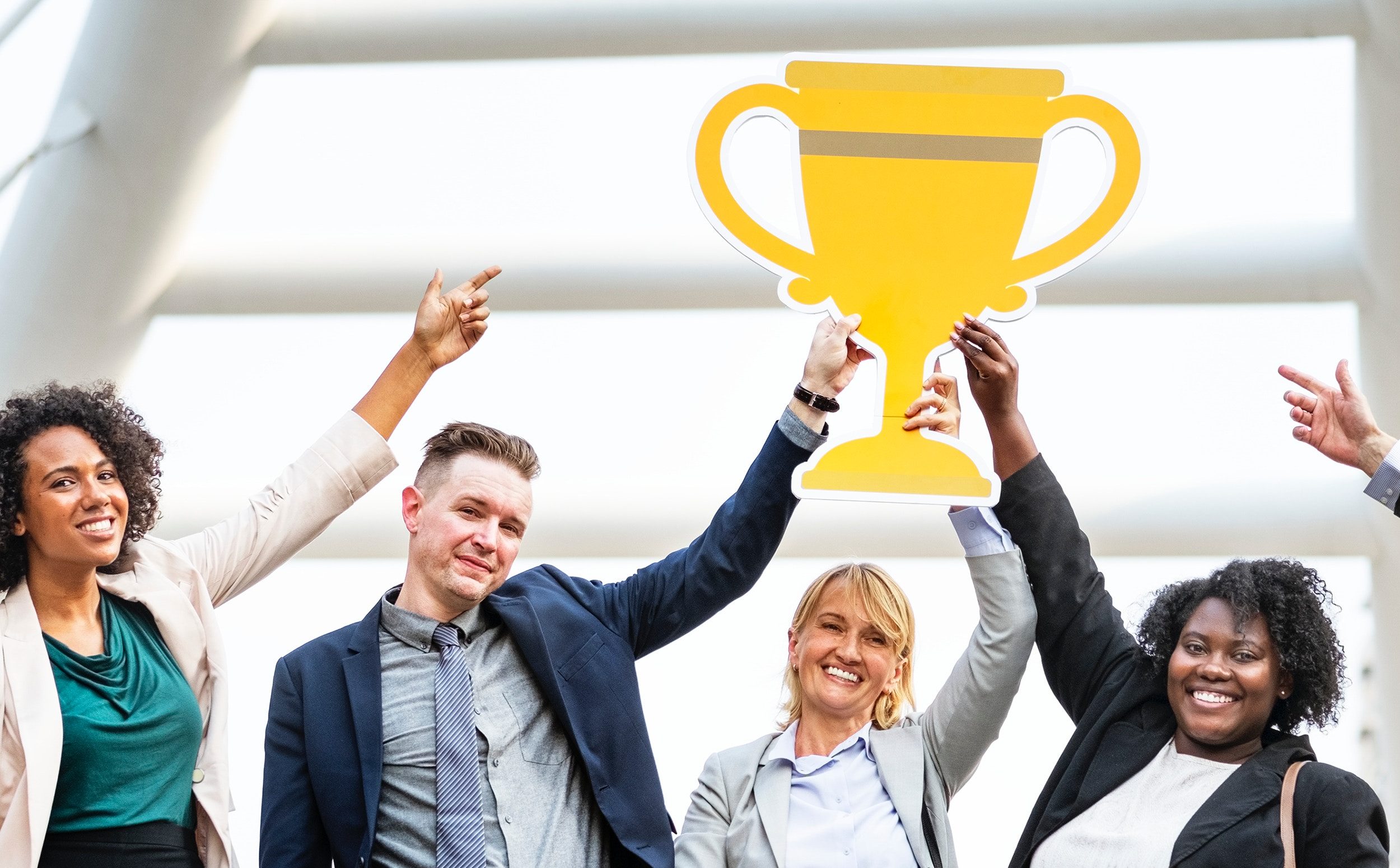 Diverse business team celebrating with a golden trophy outdoors.