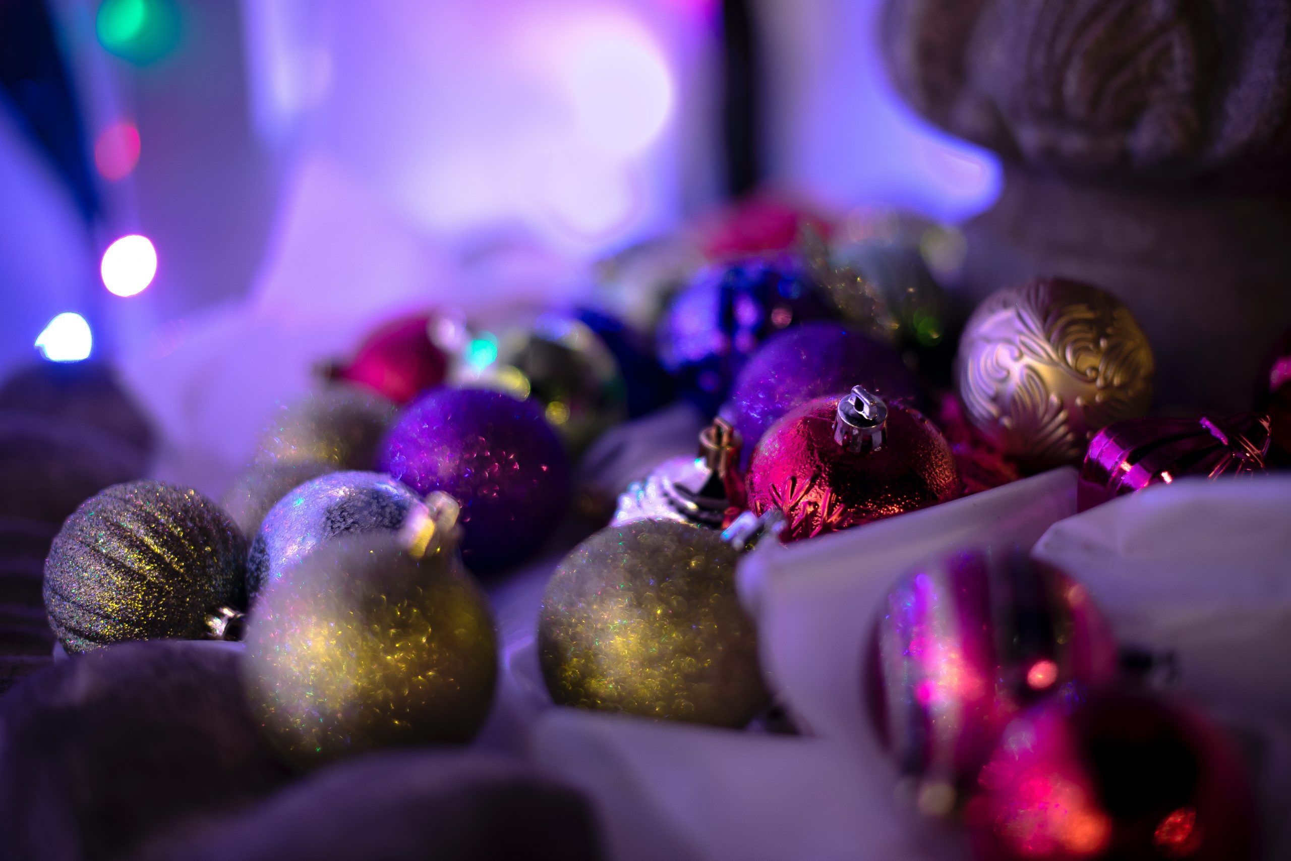 Close-up of glittery Christmas ornaments in soft focus with lights.