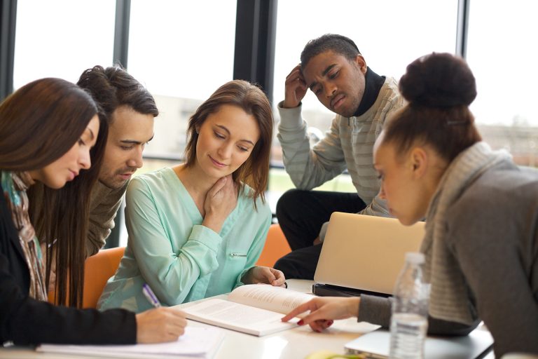 Diverse group of students or colleagues collaborating and studying together at a table.