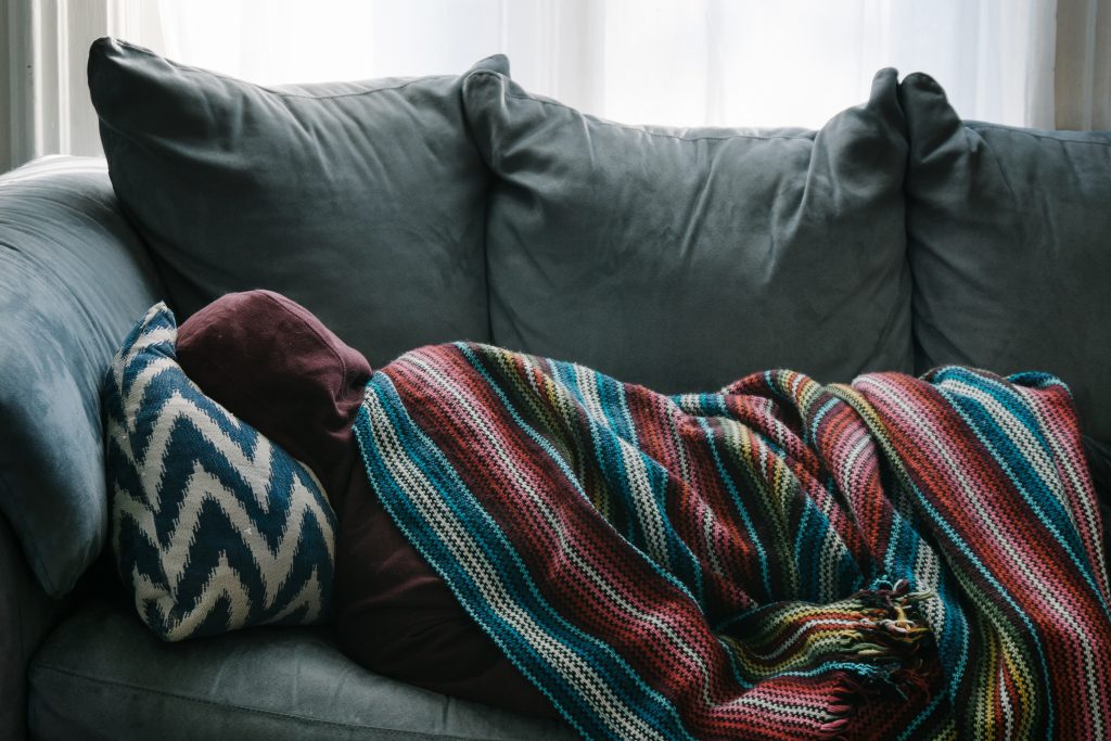 Cozy couch with a colorful striped blanket and a chevron pillow, suggesting relaxation.