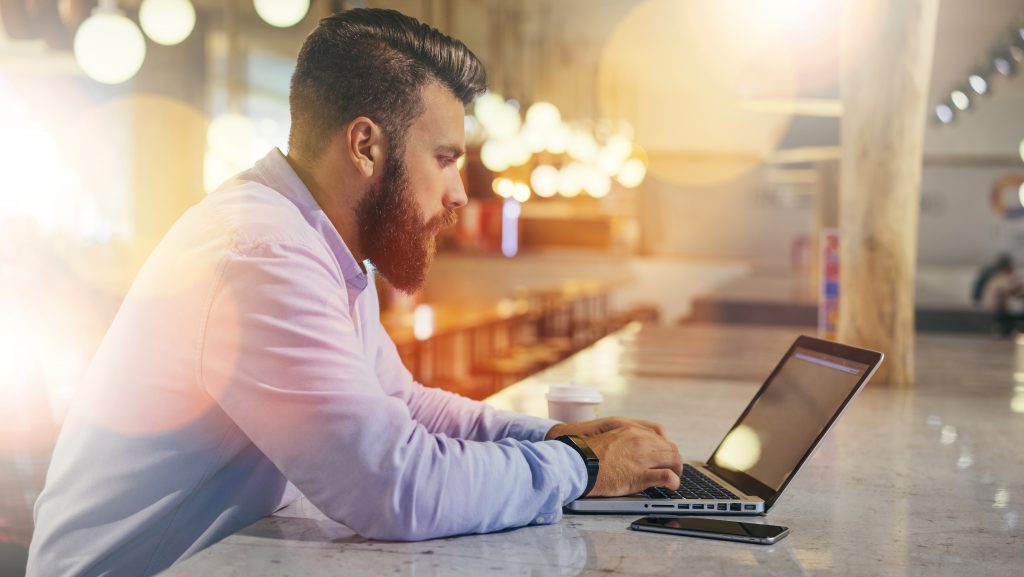 Concentrated man working on laptop in a modern workspace.