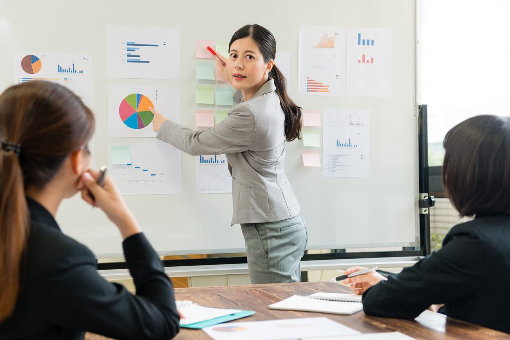 Businesswoman presenting pie chart in meeting to colleagues.