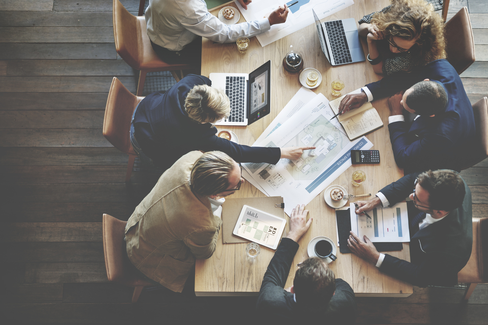 Top view of a diverse group of professionals working around a table with laptops and documents.