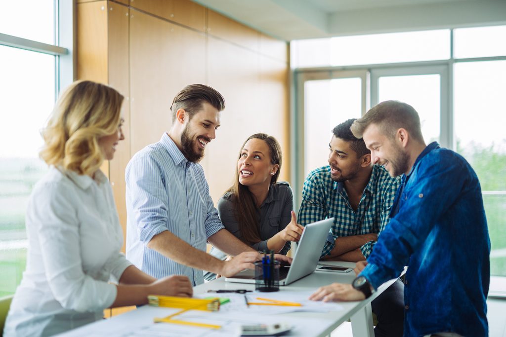 Diverse team collaborating over a laptop in a bright office setting.