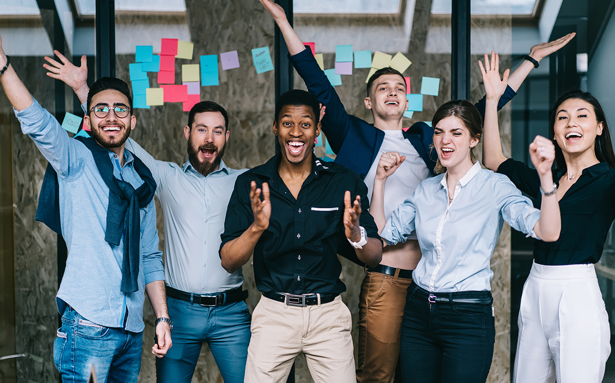 Joyful diverse team celebrating success with raised hands in the office.