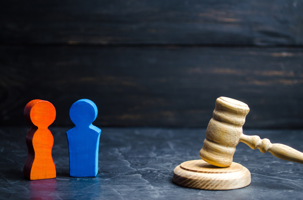 Wooden gavel and two figurines symbolizing a legal decision.