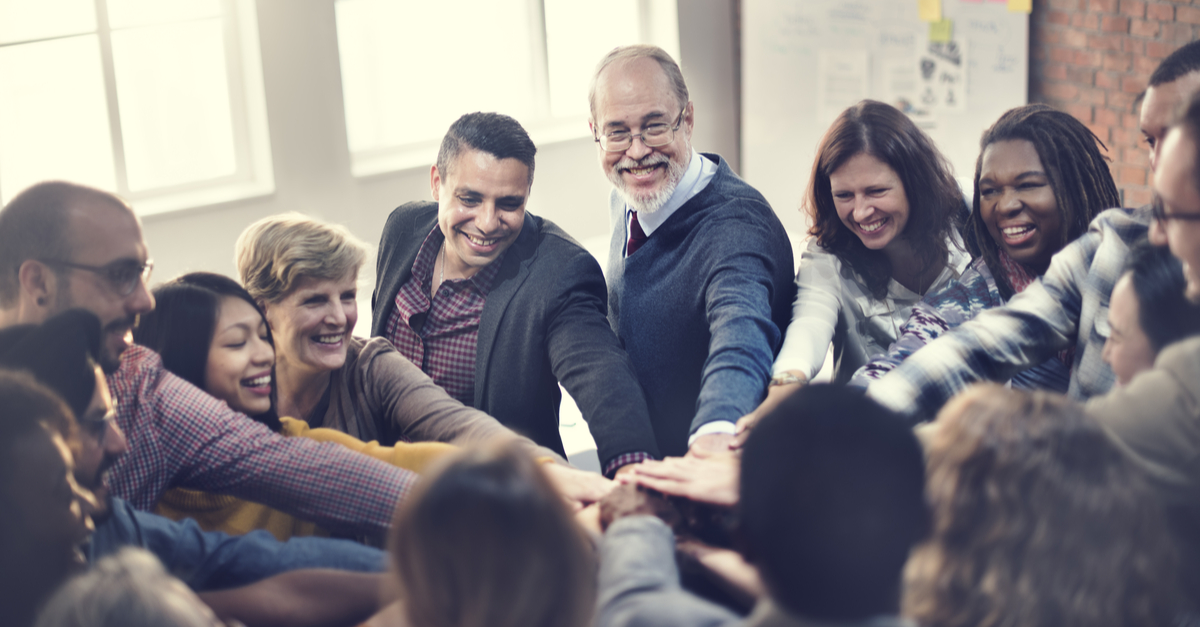 Diverse team of professionals stacking hands in a huddle for teamwork and unity.