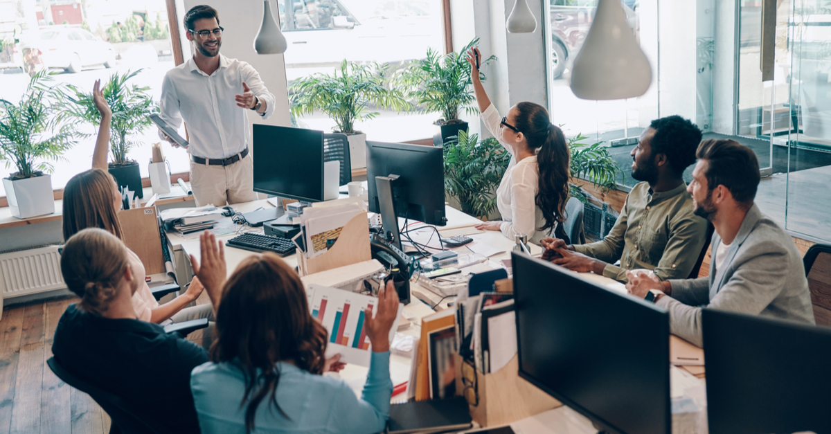 Enthusiastic leader giving a thumbs-up to a team of engaged employees.