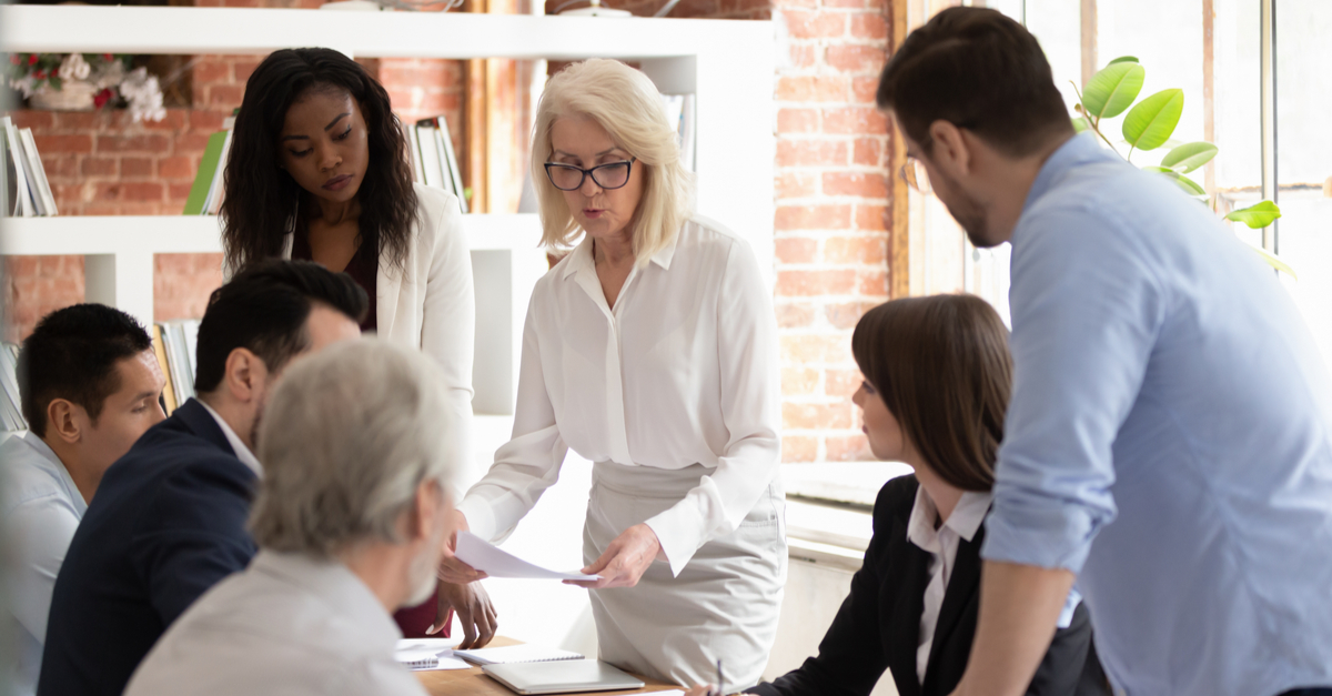 Diverse team in a meeting with a senior leader discussing documents.