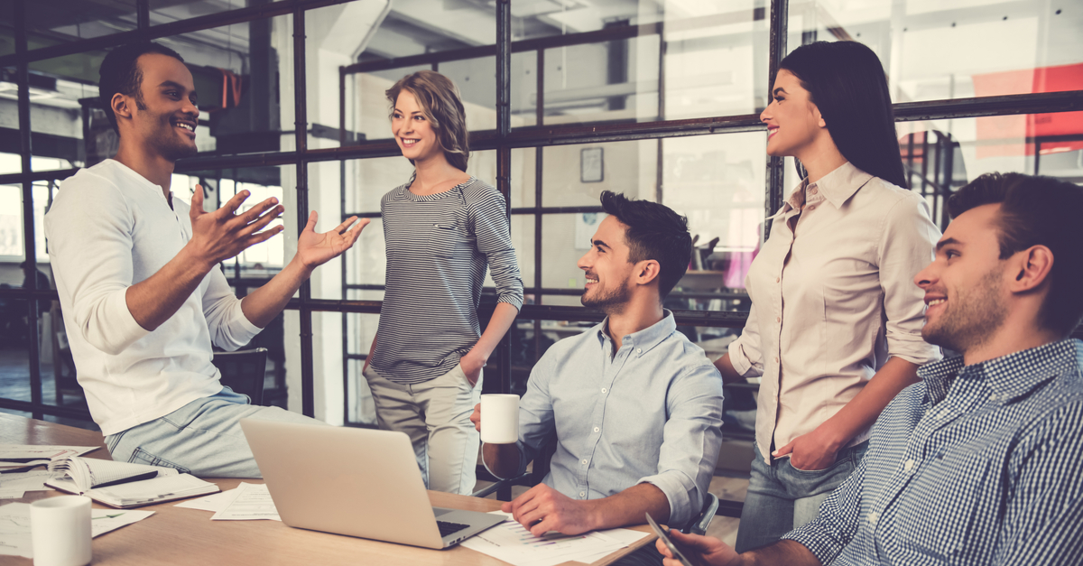 Diverse team discussing ideas around a laptop at a modern office.