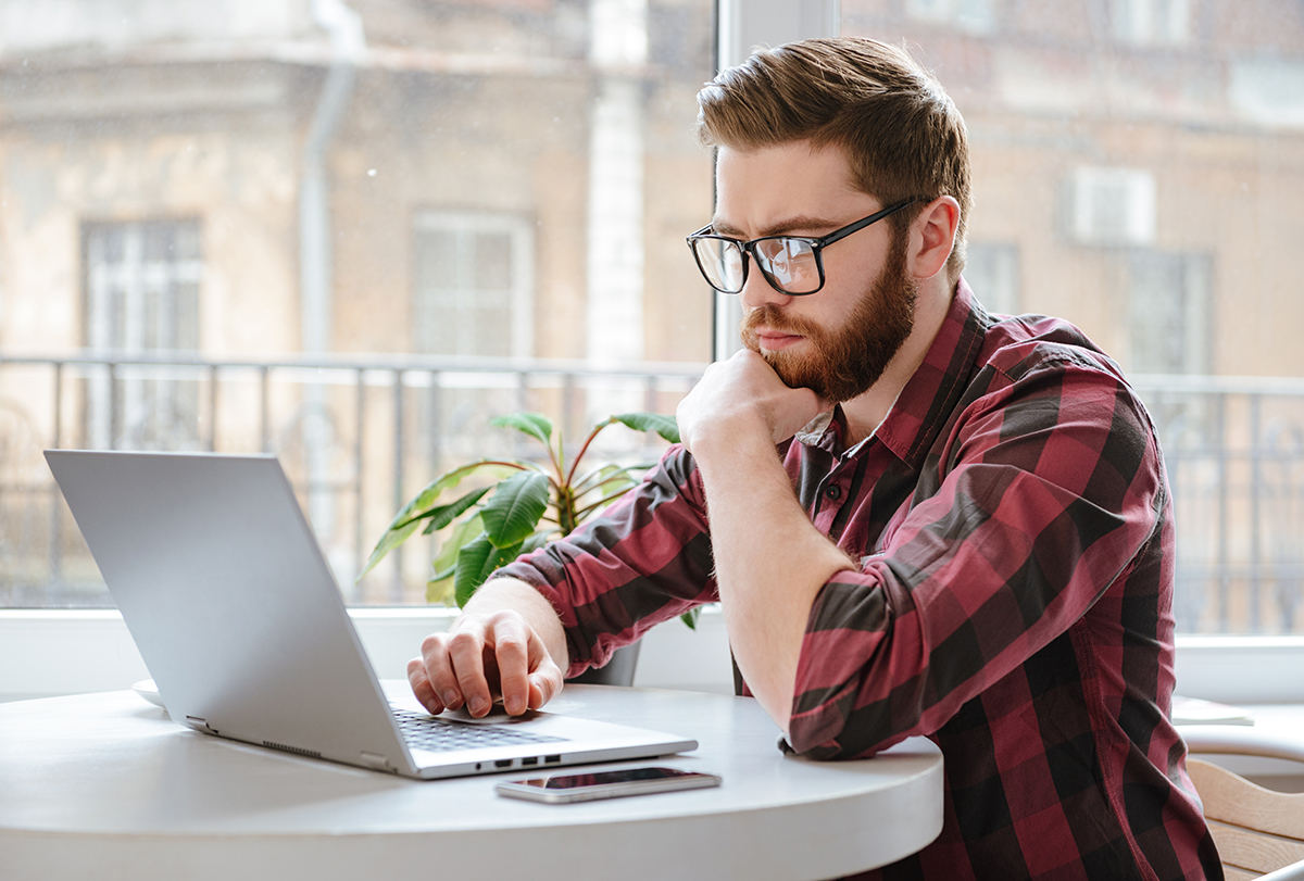 Focused man working on laptop in home office setting.