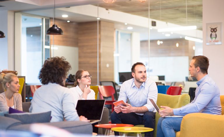 Group of professionals discussing in a modern office lounge area.