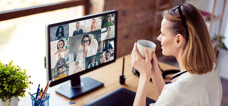 Woman attending virtual meeting with multiple colleagues on computer screen.