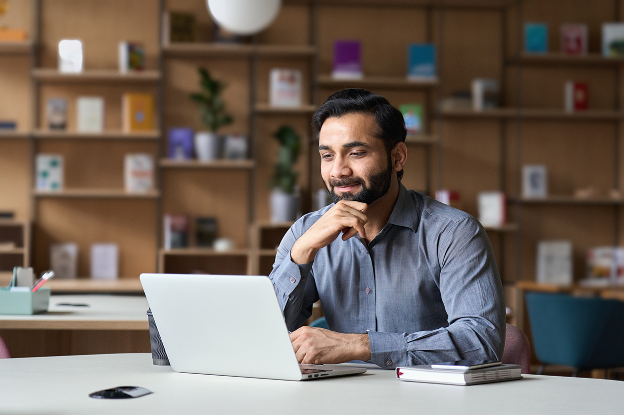 Smiling professional man working on laptop in modern office.