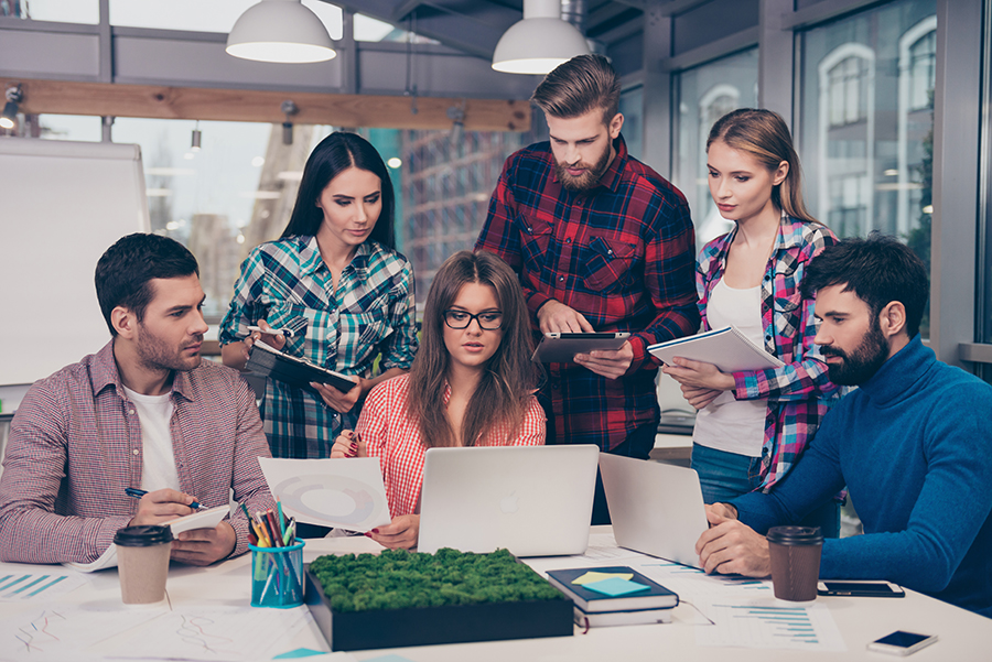 Focused team analyzing data together at a busy office desk.