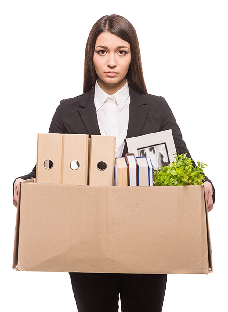 Unhappy young professional holding box with office belongings.