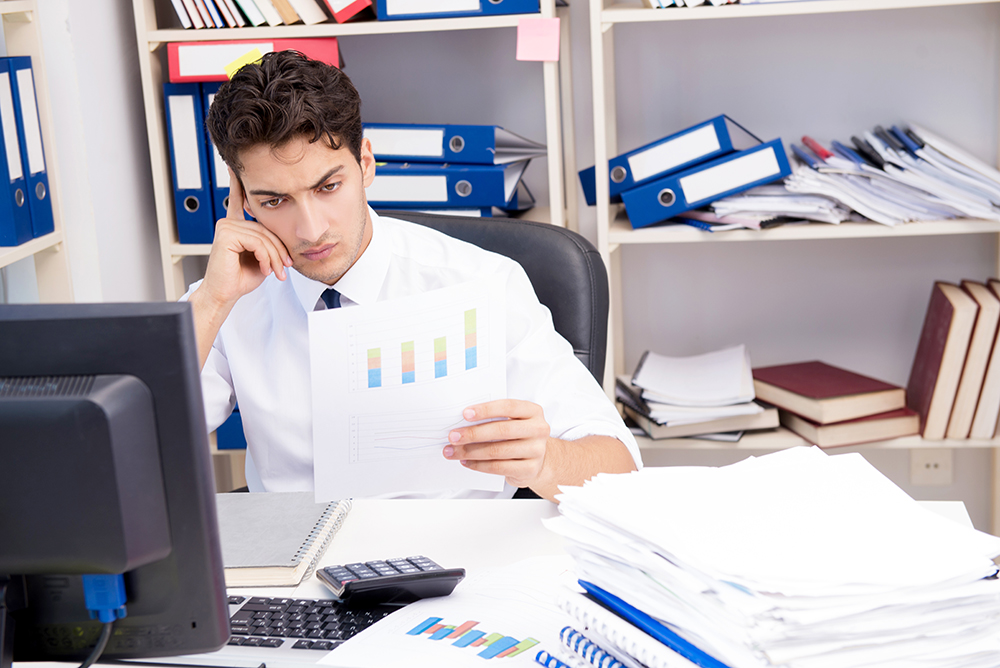 Focused HR professional analyzing bar graph report amidst paperwork.