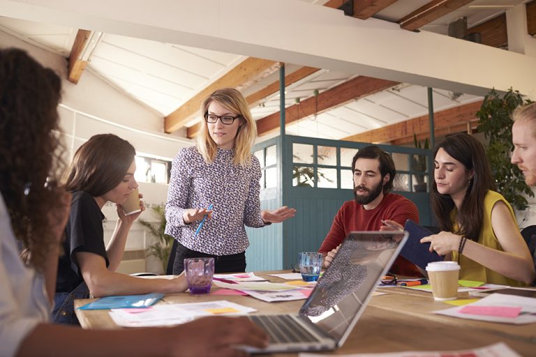 Female leader explaining strategy to diverse team at meeting.