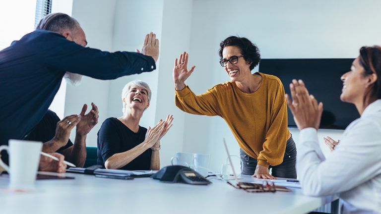 Enthusiastic team celebrating with high fives in a meeting.