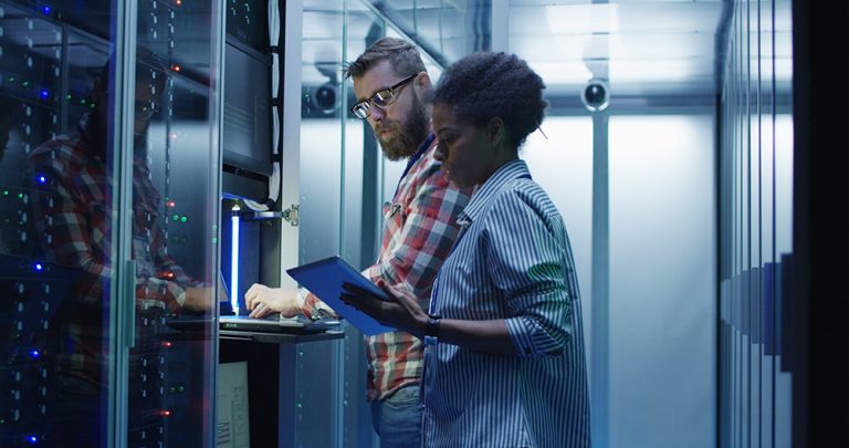 Two IT professionals working on servers in a data center.