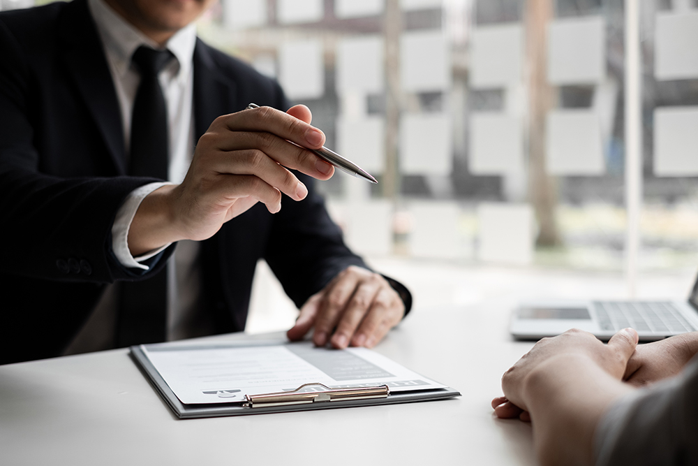 Close-up of a hiring manager explaining contract details to a candidate in an office.