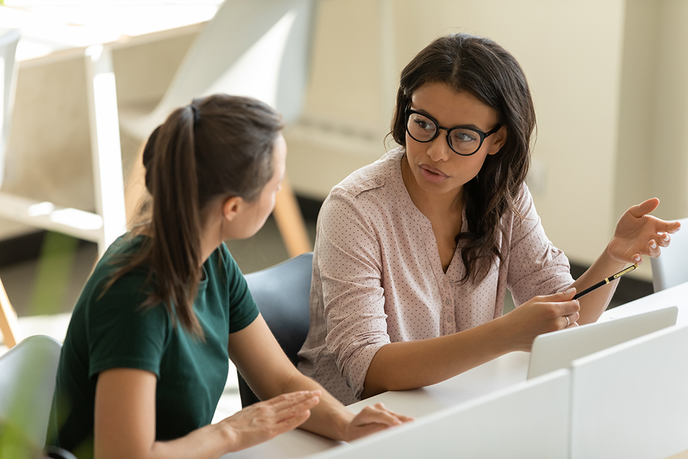 Two professional women engaged in a serious business discussion at work.