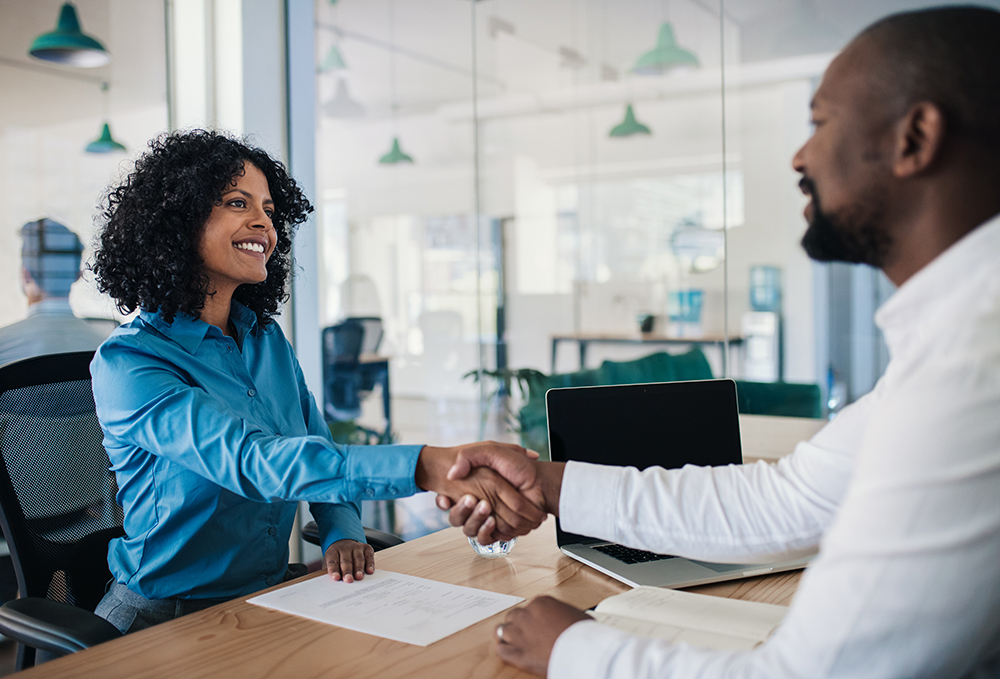 Smiling businesswoman shaking hands with colleague in modern office.