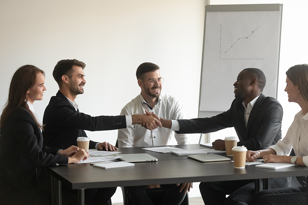 Business professionals shaking hands during a meeting with colleagues.